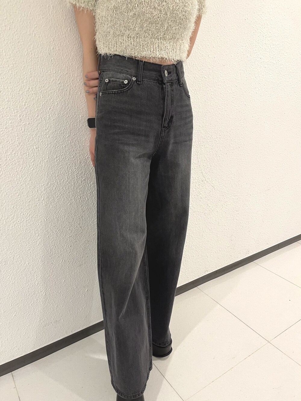 ホワイト系のニット/セーター、ブラック系のデニムパンツ、ホワイト系のハンドバッグを着用したレディースの春コーディネートの6枚目の写真