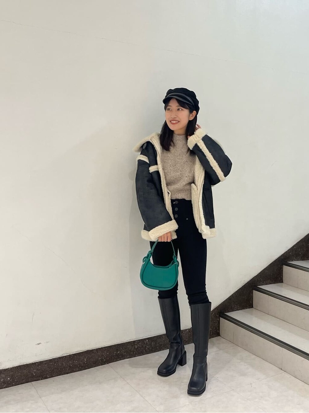 ブラック系のブーツ、ブラック系のムートンコート、ブラック系のデニムパンツを着用したレディースの秋コーディネートの2枚目の写真