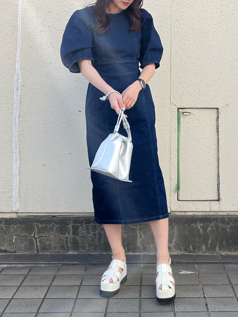 ブルー系のワンピース、シルバー系のハンドバッグ、ホワイト系のサンダルを着用したレディースの春コーディネートの4枚目の写真
