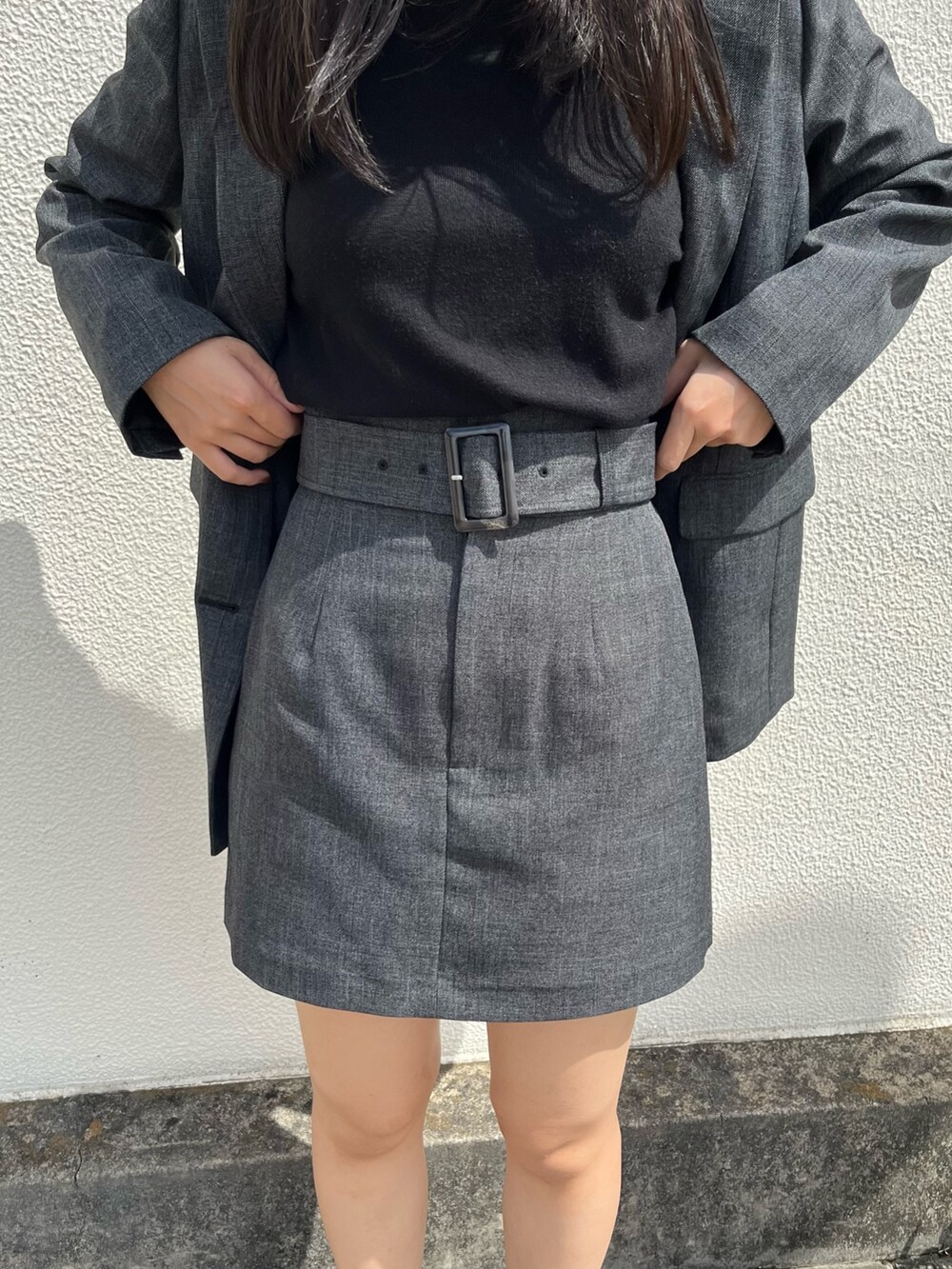 グレー系のテーラードジャケット、グレー系のスカート、ブラック系のブーツを着用したレディースの秋コーディネートの5枚目の写真