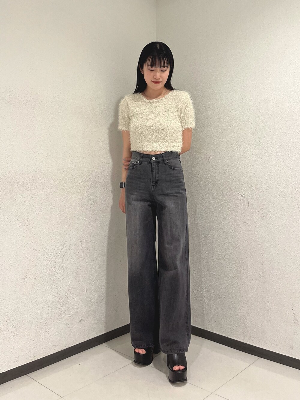 ホワイト系のニット/セーター、ブラック系のデニムパンツ、ホワイト系のハンドバッグを着用したレディースの春コーディネートの3枚目の写真