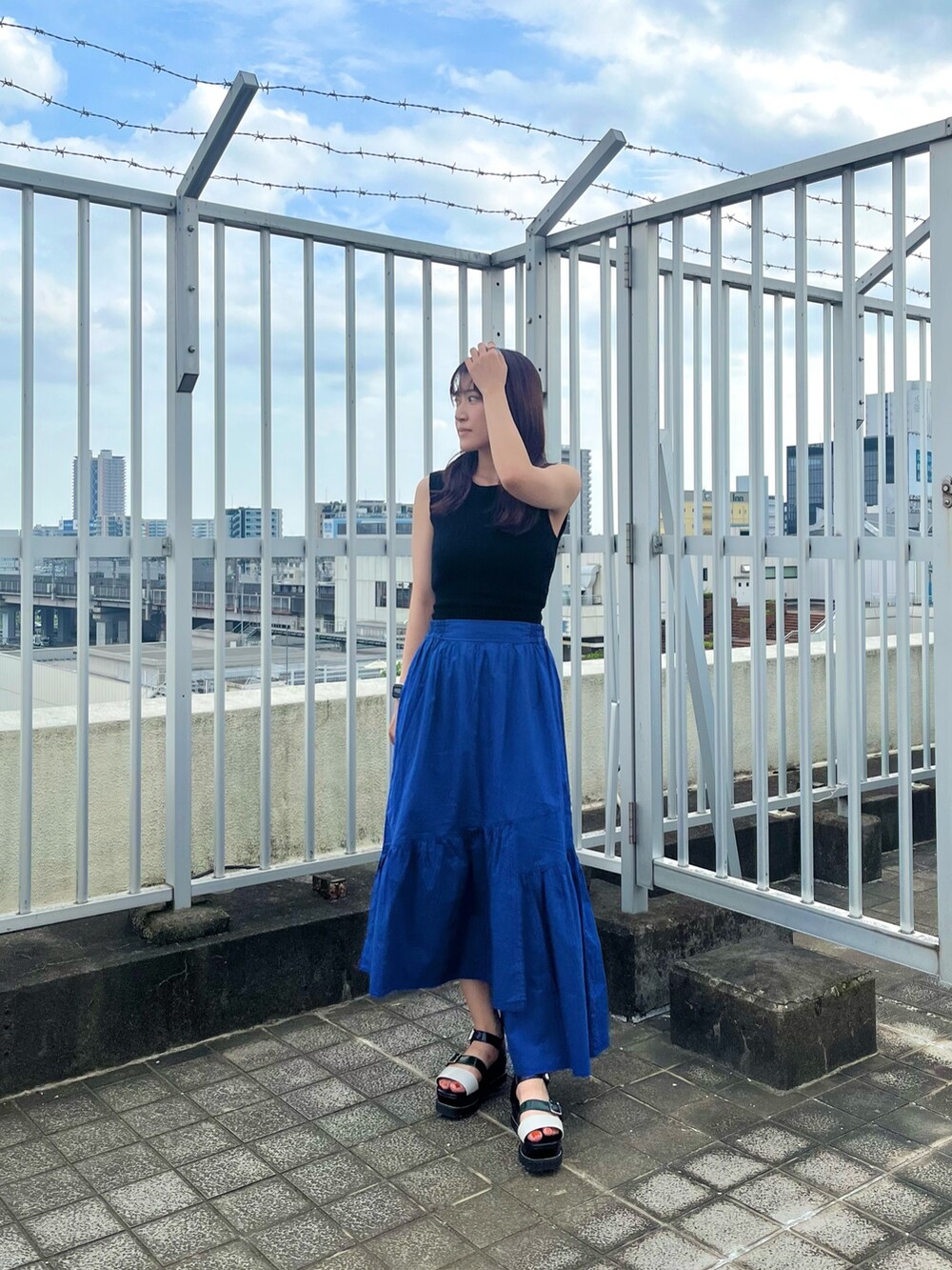 ブラック系のタンクトップ、ブルー系のスカートを着用したレディースの夏コーディネートの2枚目の写真