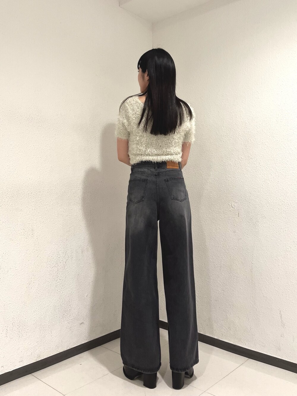 ホワイト系のニット/セーター、ブラック系のデニムパンツ、ホワイト系のハンドバッグを着用したレディースの春コーディネートの4枚目の写真