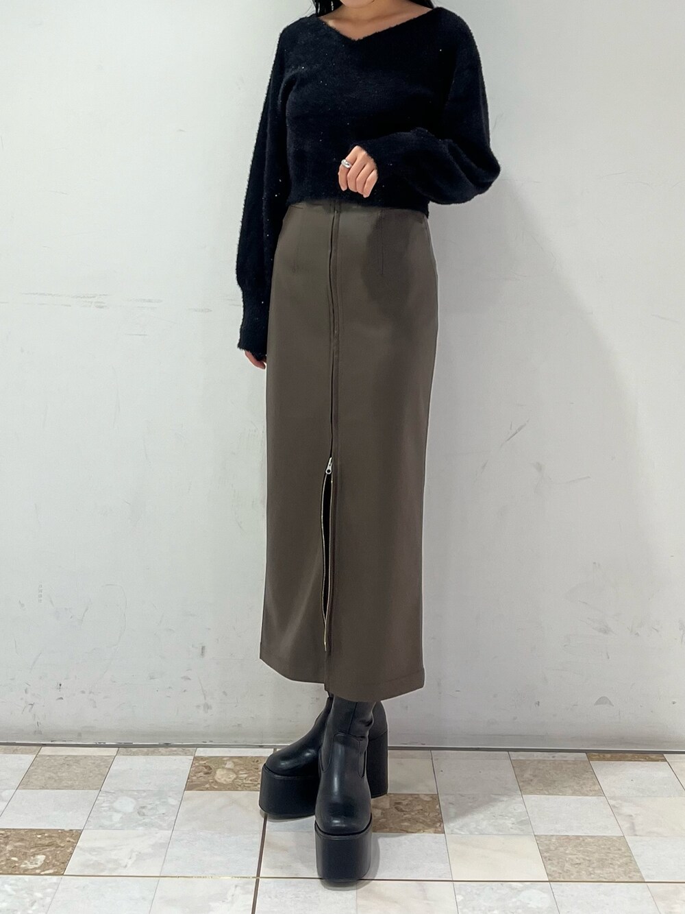 ブラウン系のスカート、ブラック系のニット/セーターを着用したレディースの秋コーディネートの4枚目の写真