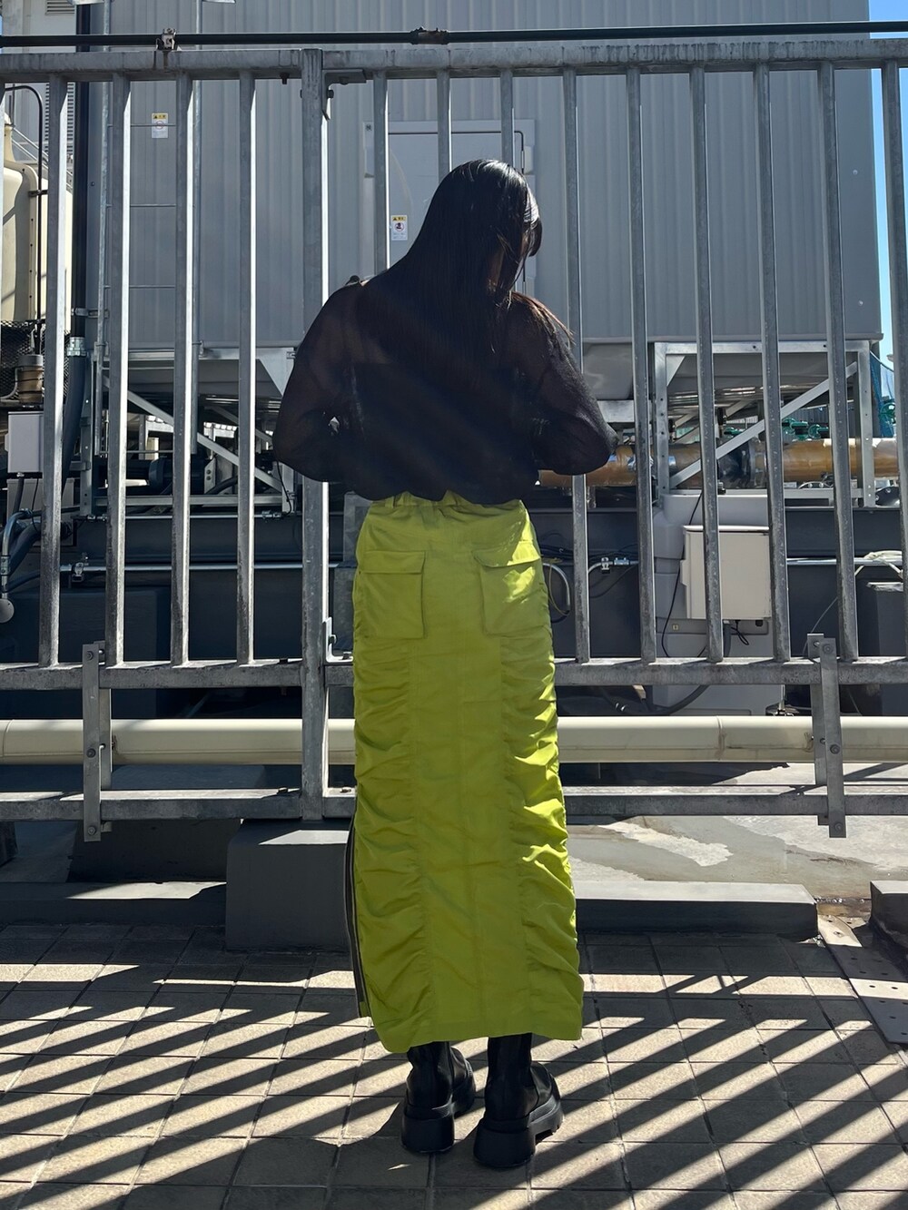 ブラック系のTシャツ/カットソー、グリーン系のスカート、ブラック系のブーツを着用したレディースの春コーディネートの4枚目の写真