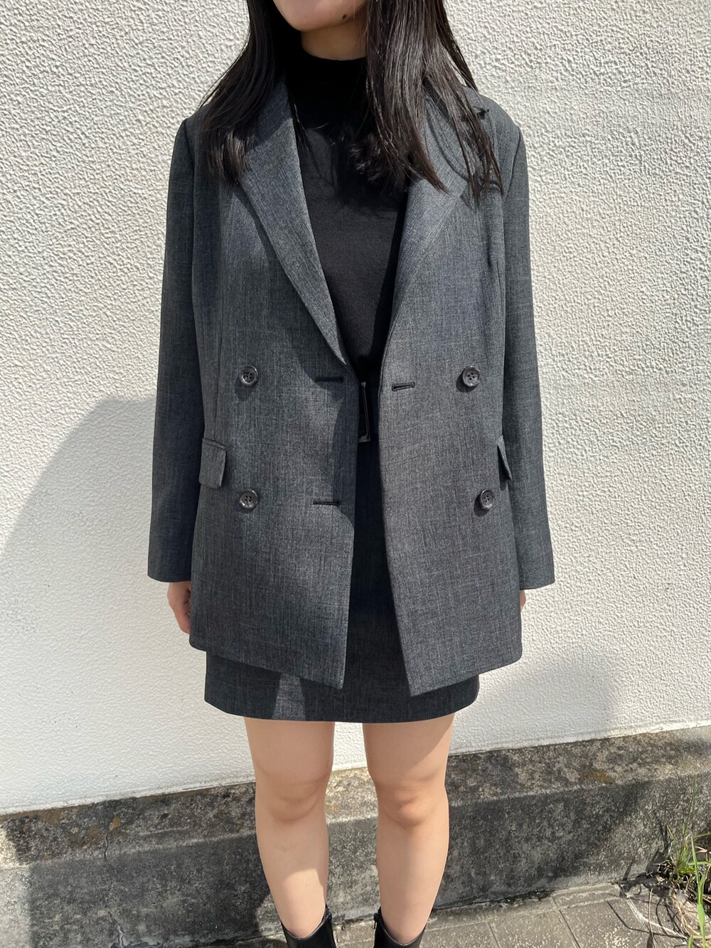 グレー系のテーラードジャケット、グレー系のスカート、ブラック系のブーツを着用したレディースの秋コーディネートの4枚目の写真