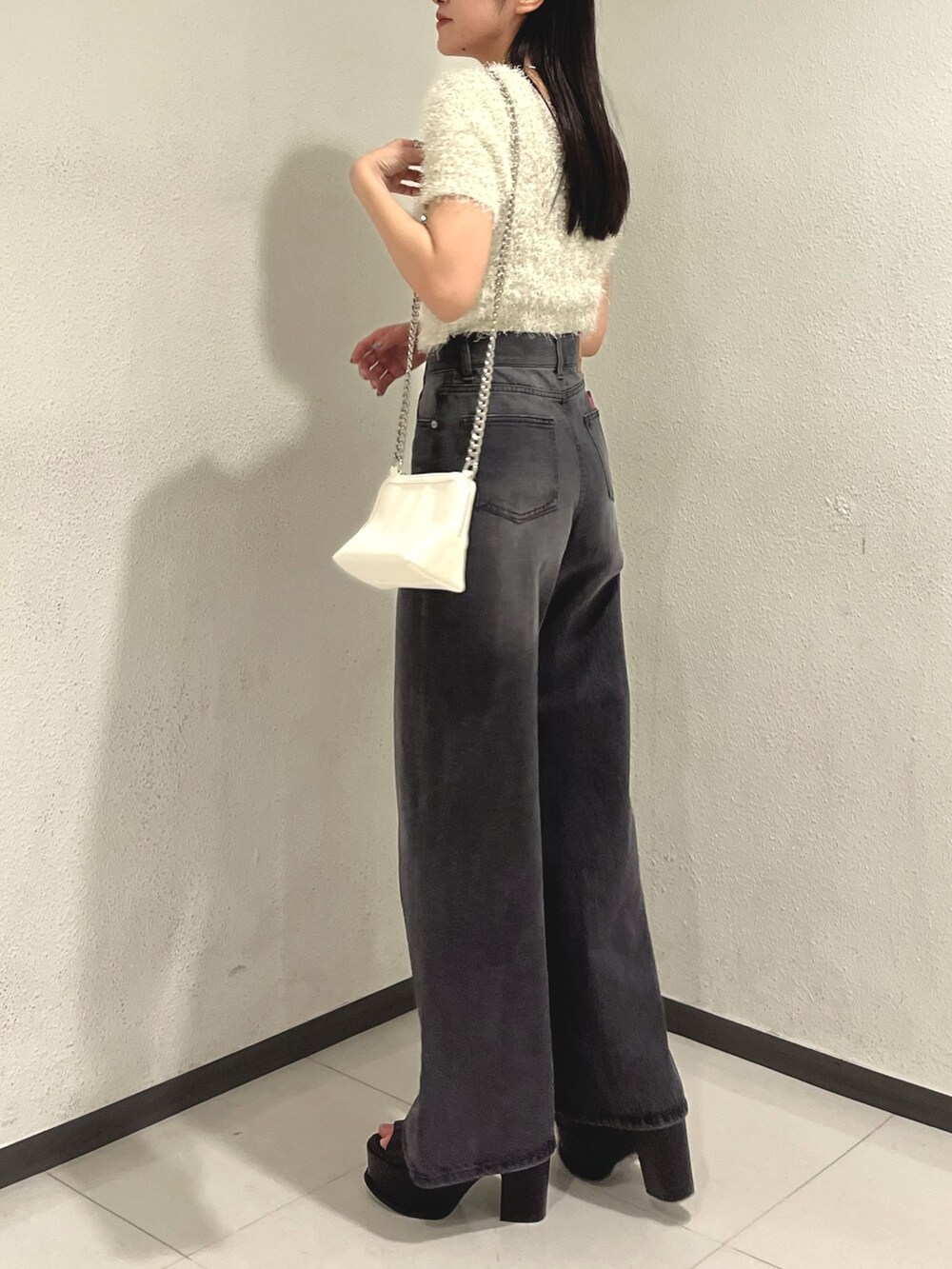 ホワイト系のニット/セーター、ブラック系のデニムパンツ、ホワイト系のハンドバッグを着用したレディースの春コーディネートの5枚目の写真
