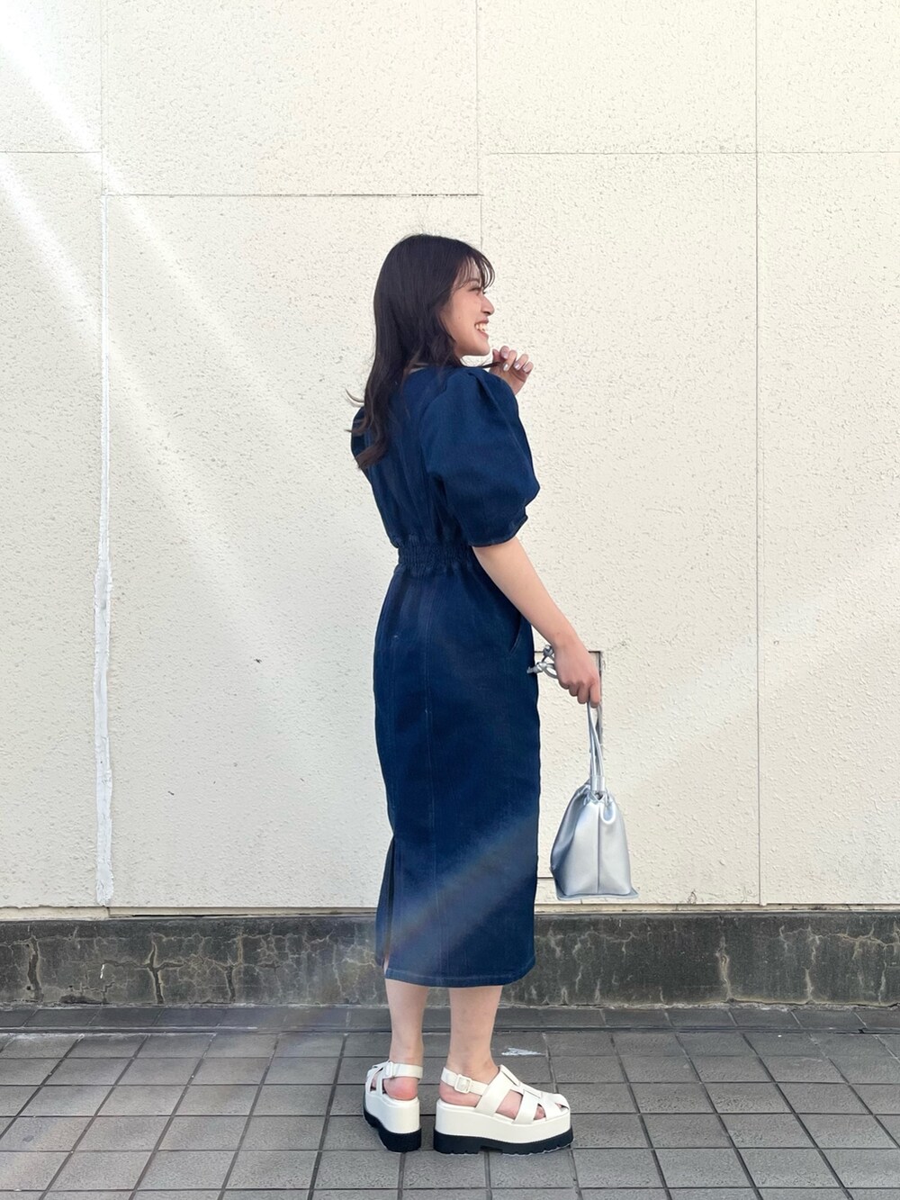 ブルー系のワンピース、シルバー系のハンドバッグ、ホワイト系のサンダルを着用したレディースの春コーディネートの2枚目の写真