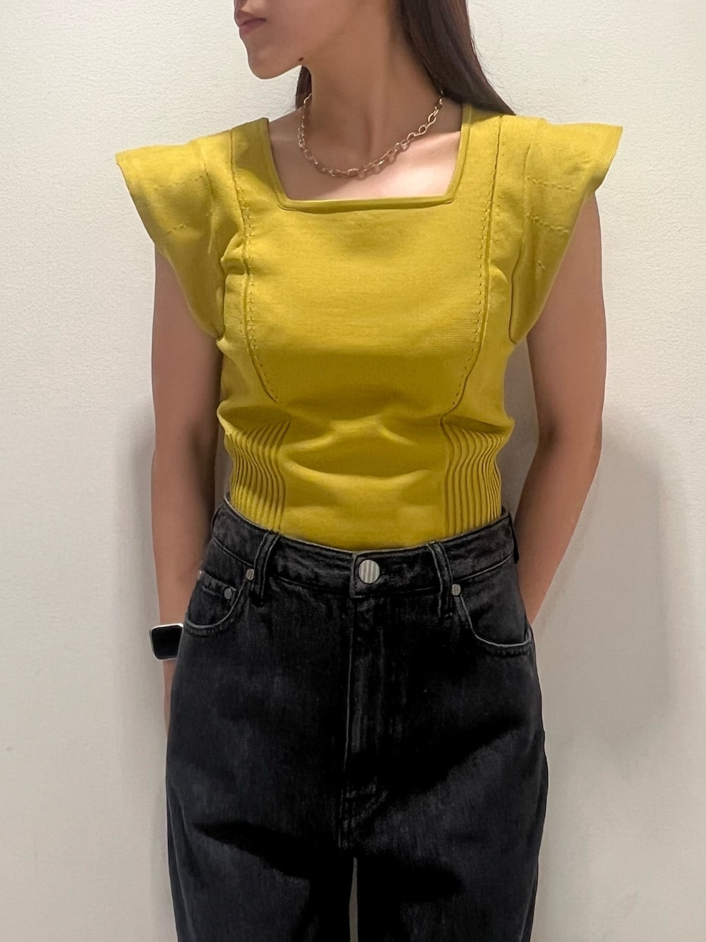 イエロー系のニット/セーター、ブラック系のデニムパンツを着用したレディースの夏コーディネートの3枚目の写真