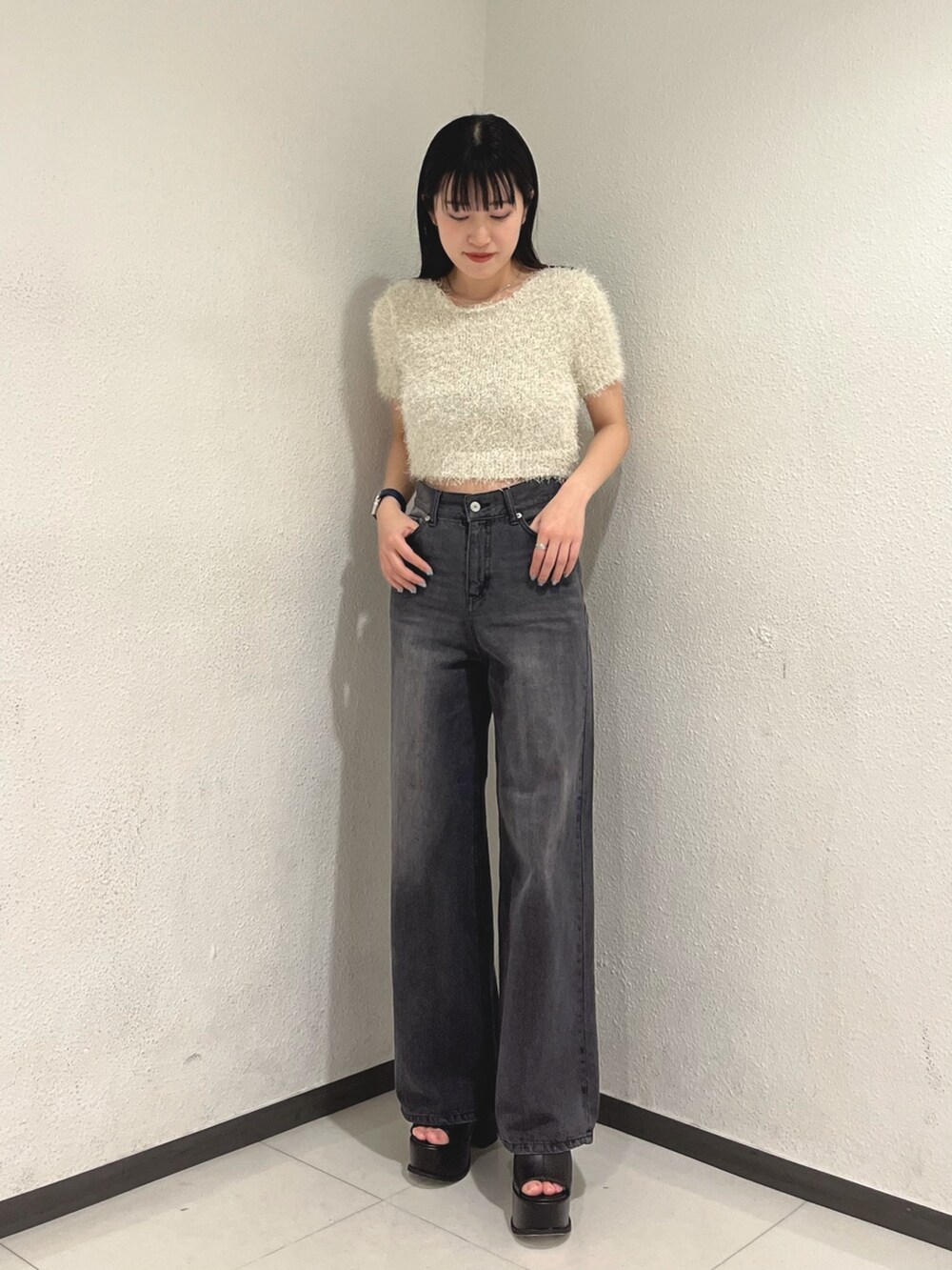 ホワイト系のニット/セーター、ブラック系のデニムパンツ、ホワイト系のハンドバッグを着用したレディースの春コーディネートの2枚目の写真