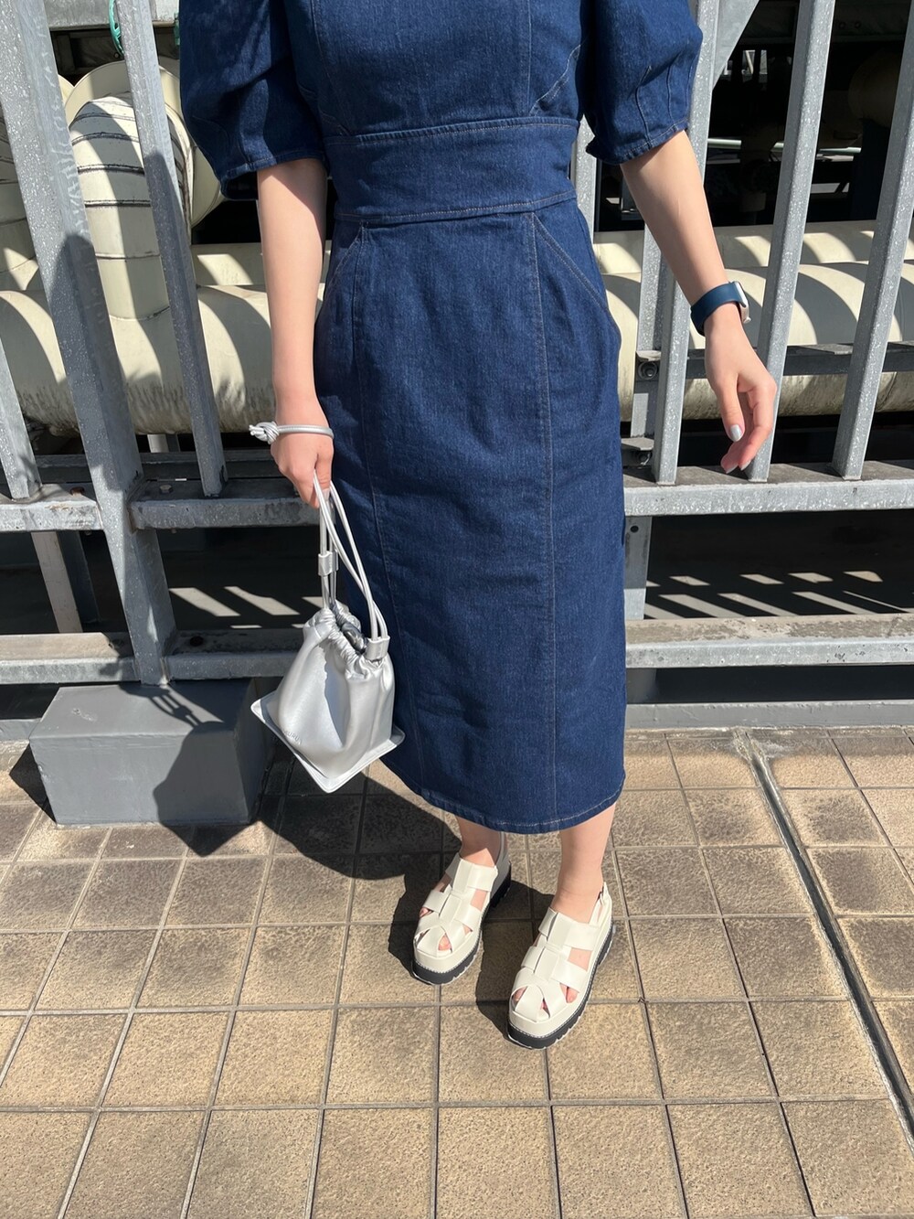 ブルー系のワンピース、シルバー系のハンドバッグ、ホワイト系のサンダルを着用したレディースの春コーディネートの6枚目の写真