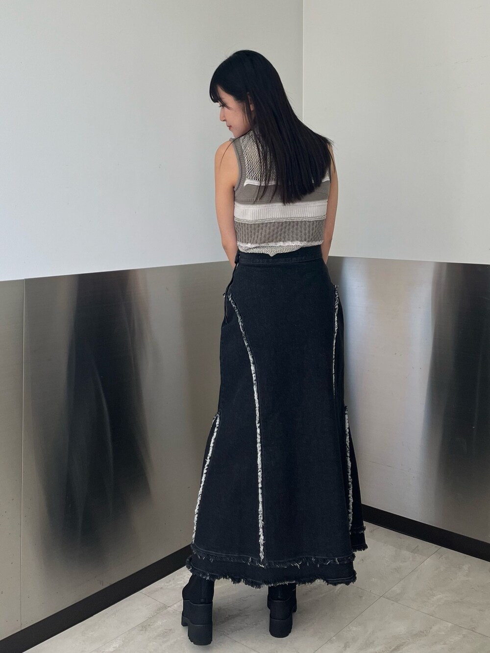 グレー系のニット/セーター、ブラック系のデニムスカート、ブラック系のブーツを着用したレディースの春コーディネートの4枚目の写真