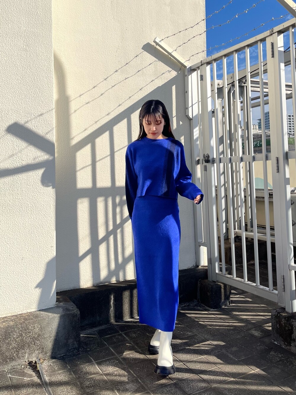 ブルー系のニット/セーター、ブルー系のスカート、ホワイト系のブーツを着用したレディースの冬コーディネートの2枚目の写真