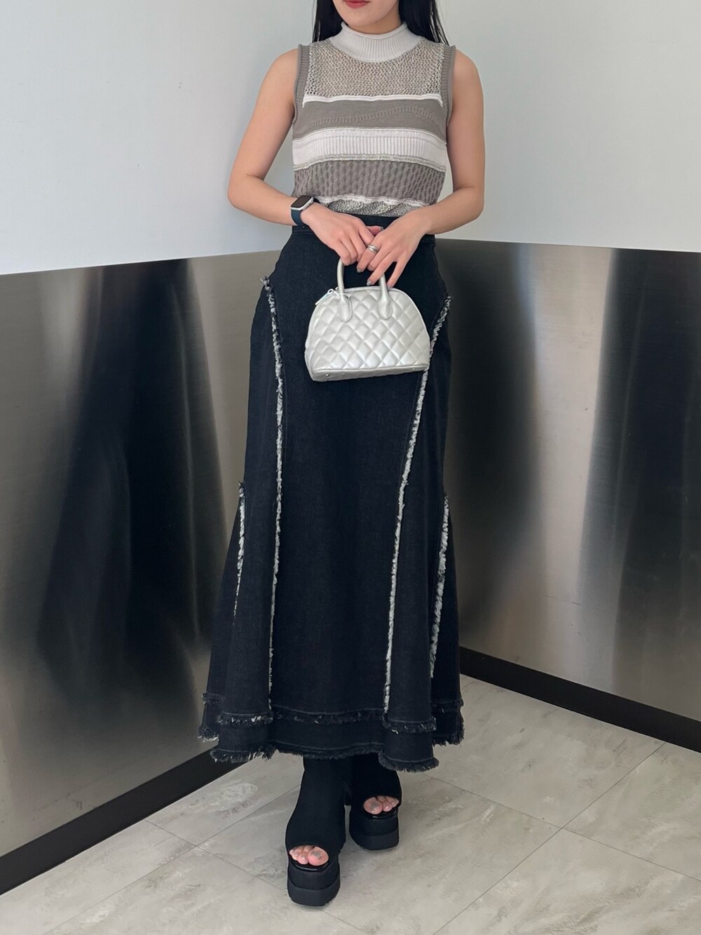 グレー系のニット/セーター、ブラック系のデニムスカート、ブラック系のブーツを着用したレディースの春コーディネートの5枚目の写真