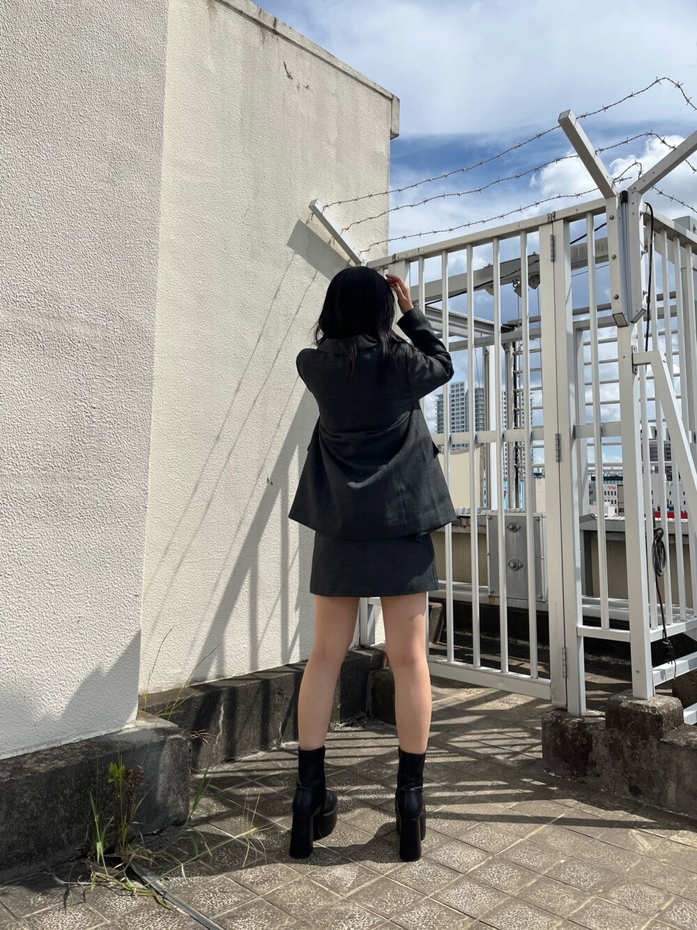 グレー系のテーラードジャケット、グレー系のスカート、ブラック系のブーツを着用したレディースの秋コーディネートの3枚目の写真