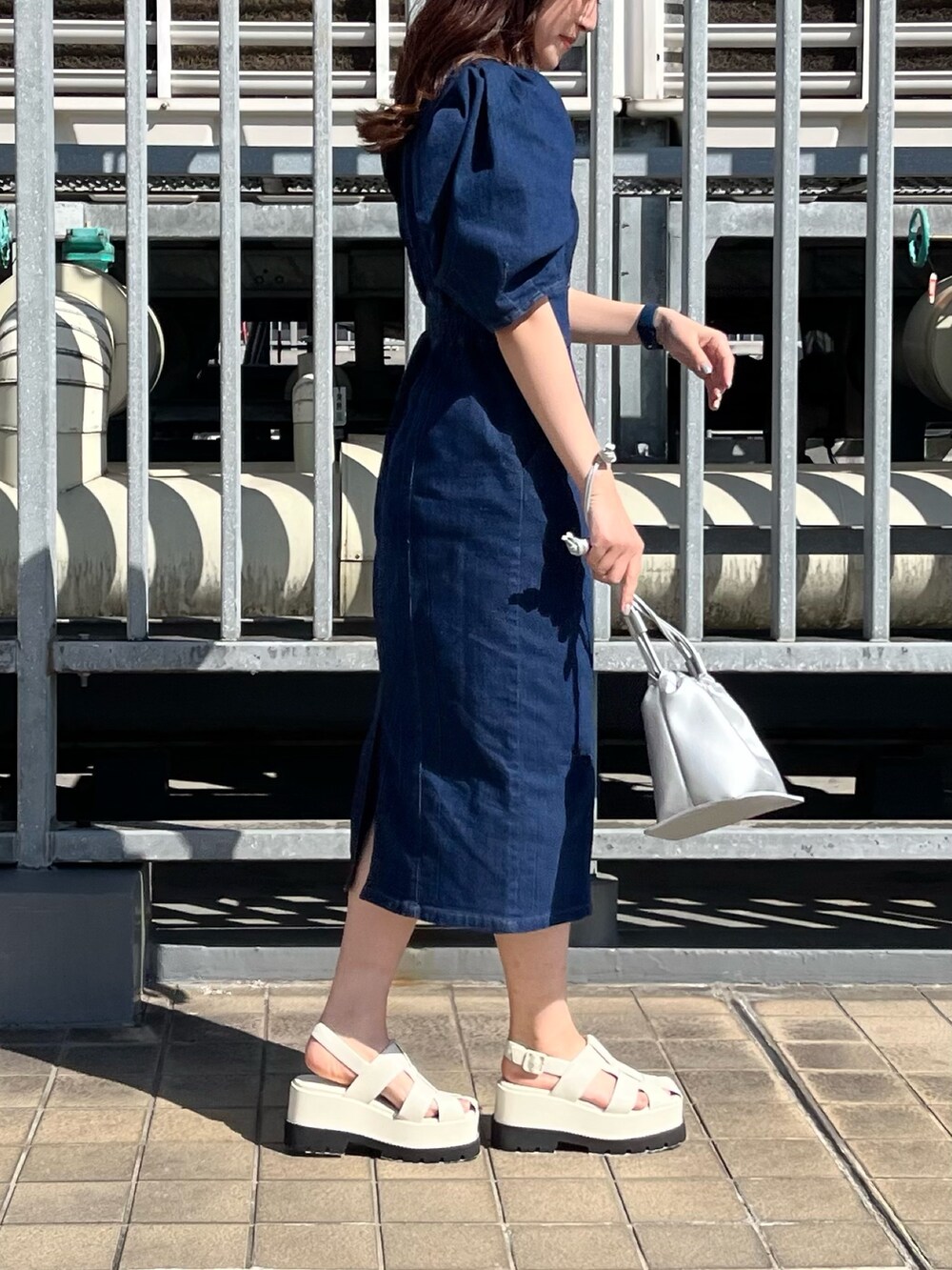 ブルー系のワンピース、シルバー系のハンドバッグ、ホワイト系のサンダルを着用したレディースの春コーディネートの5枚目の写真