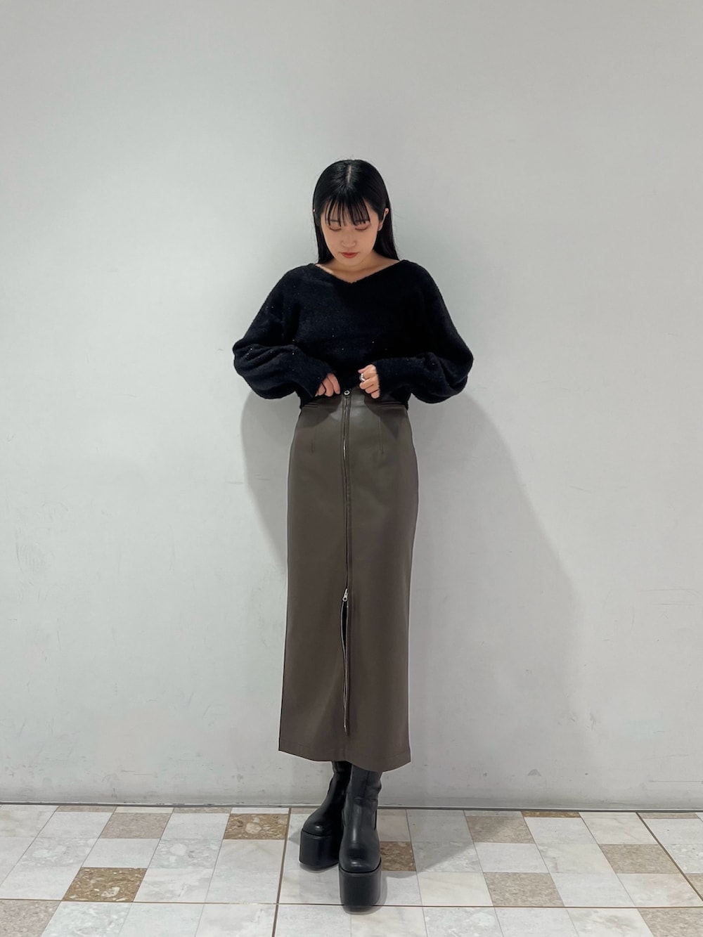 ブラウン系のスカート、ブラック系のニット/セーターを着用したレディースの秋コーディネートの2枚目の写真