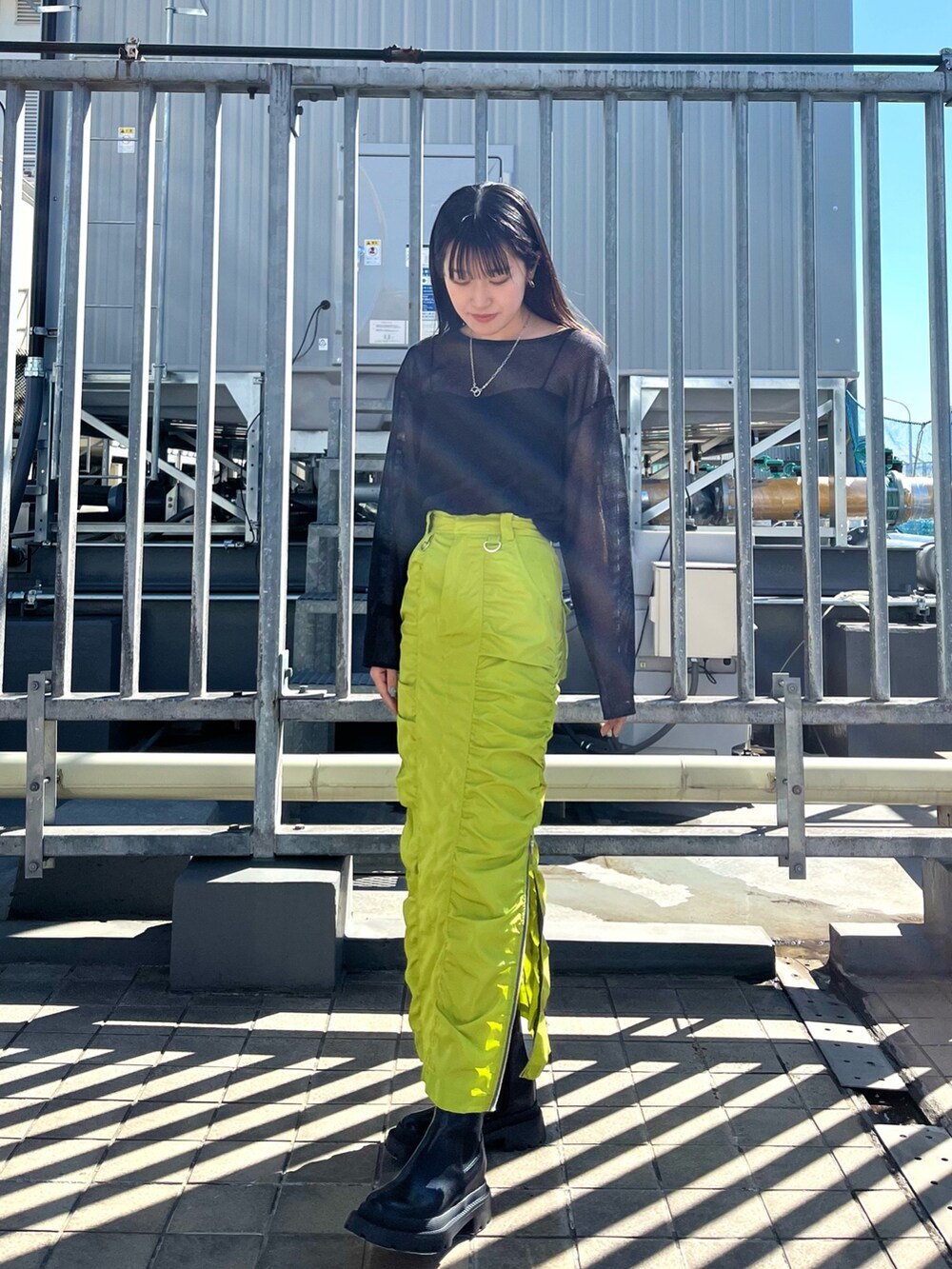 ブラック系のTシャツ/カットソー、グリーン系のスカート、ブラック系のブーツを着用したレディースの春コーディネートの2枚目の写真