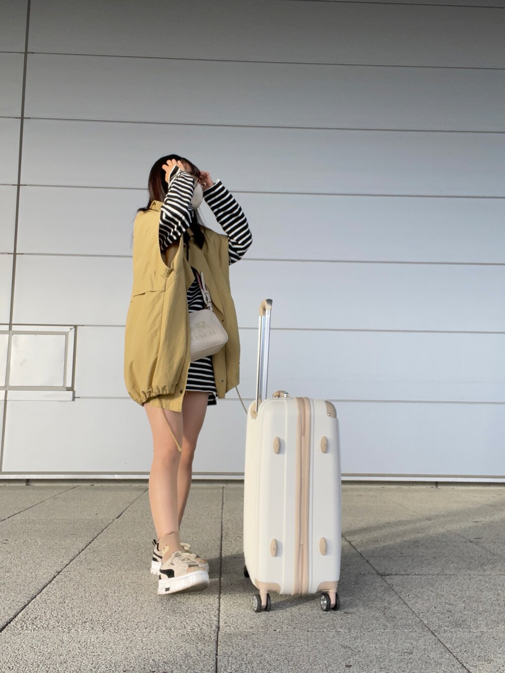 ベージュ系のスニーカー、ホワイト系のデニムパンツ、ブラック系のチュニックを着用したレディースの秋コーディネートの2枚目の写真