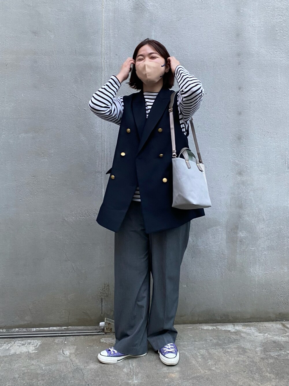 グレー系のショルダーバッグ、ブルー系のベスト、ホワイト系のTシャツ/カットソーを着用したレディースの春コーディネートの2枚目の写真