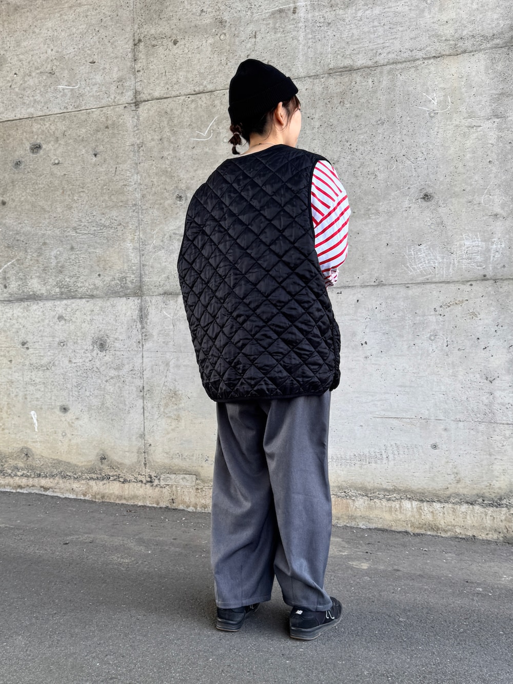 レッド系のTシャツ/カットソー、ブラック系のベスト、ブラック系のニットキャップ/ビーニーを着用したレディースの春コーディネートの3枚目の写真