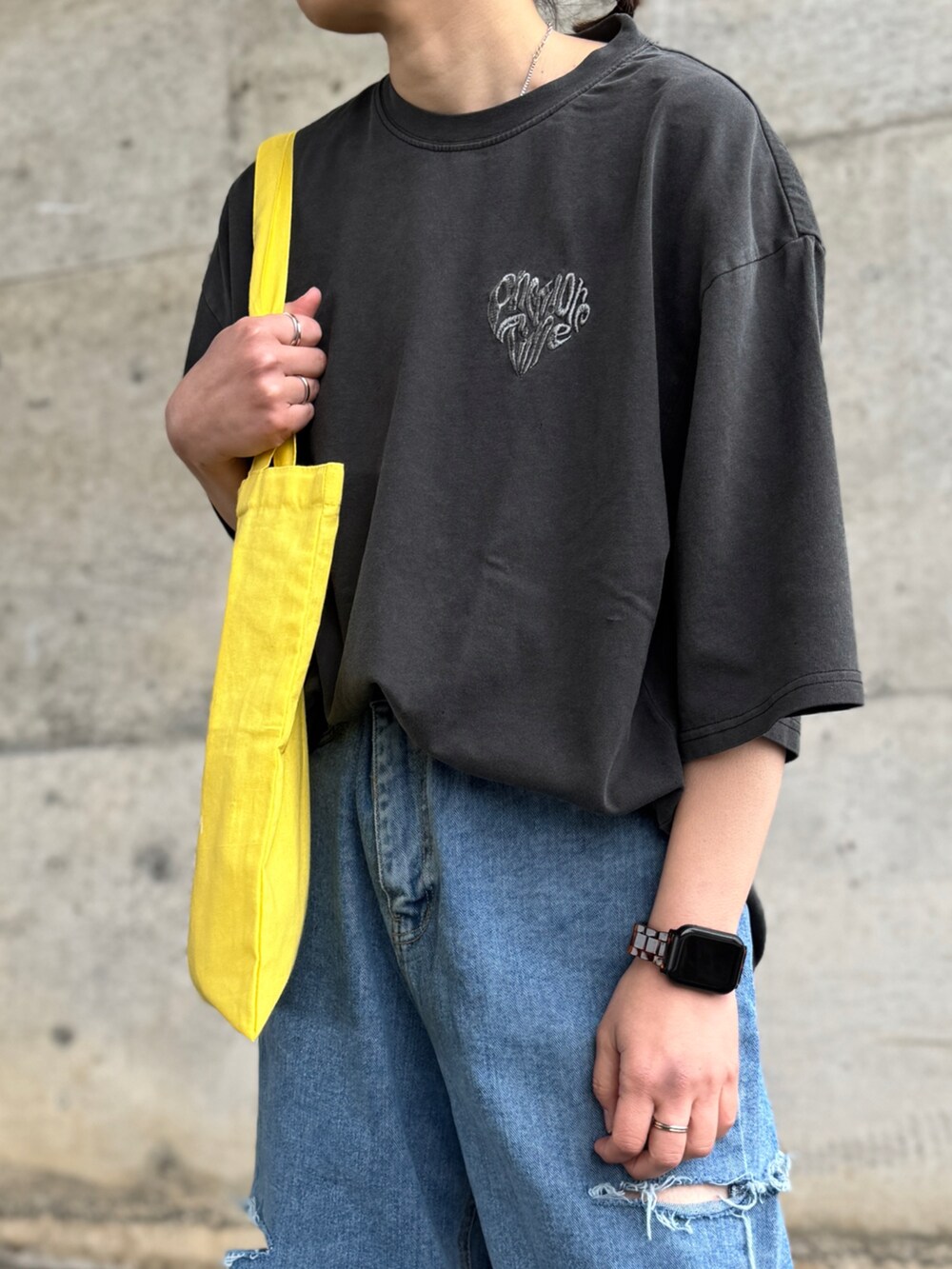 グレー系のTシャツ/カットソー、イエロー系のトートバッグ、ブラック系のキャップを着用したレディースの春コーディネートの4枚目の写真