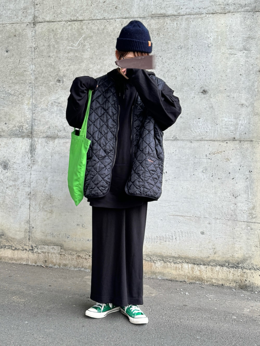 ブラック系のベスト、グリーン系のスニーカー、グリーン系のトートバッグを着用したレディースの冬コーディネートの2枚目の写真