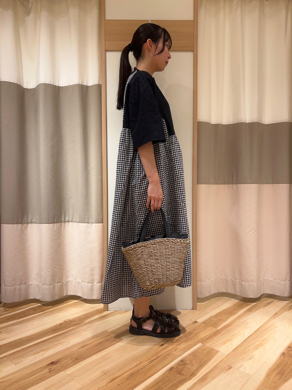 ブラック系のワンピース、ブラック系のハンドバッグ、ブラック系のサンダルを着用したレディースの春コーディネートの2枚目の写真