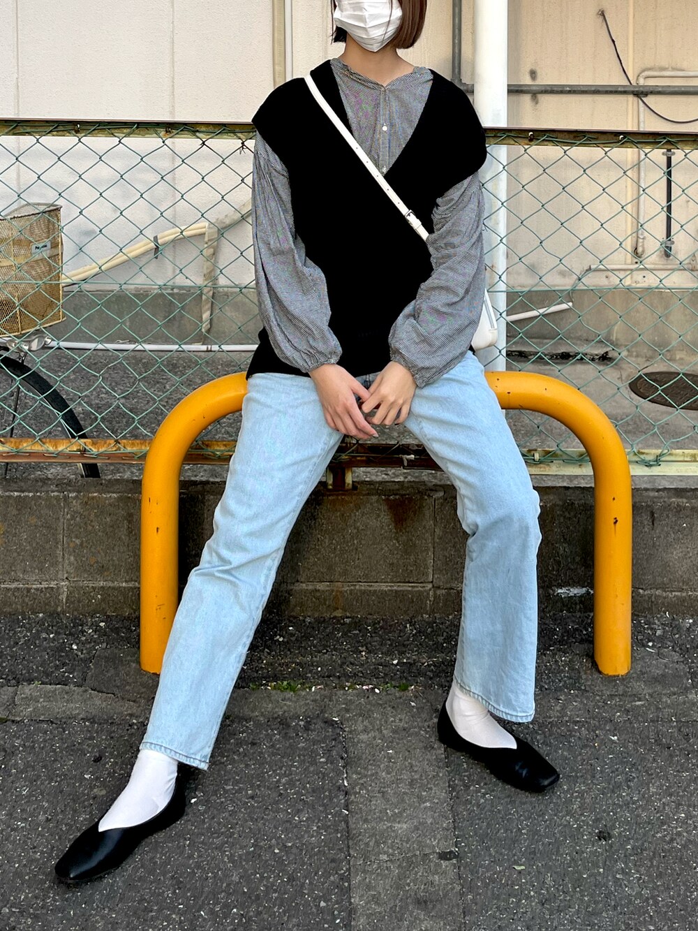 ブラック系のニット/セーター、ホワイト系のバッグ、ブルー系のデニムパンツを着用したレディースの夏コーディネートの2枚目の写真