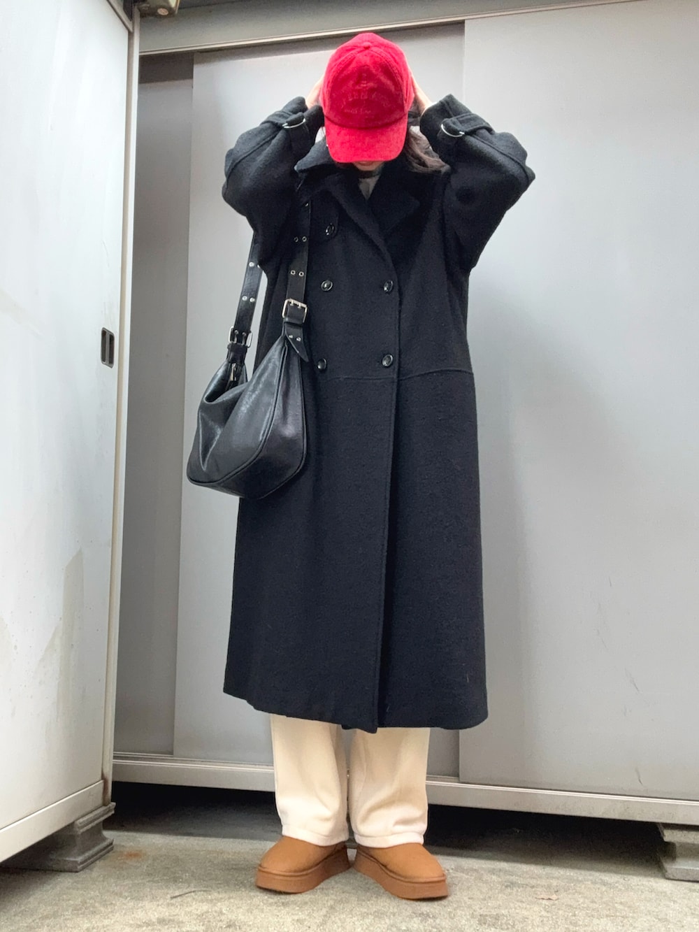 ホワイト系のパンツ、イエロー系のブーツ、ブラック系のチェスターコートを着用したレディースの冬コーディネートの2枚目の写真