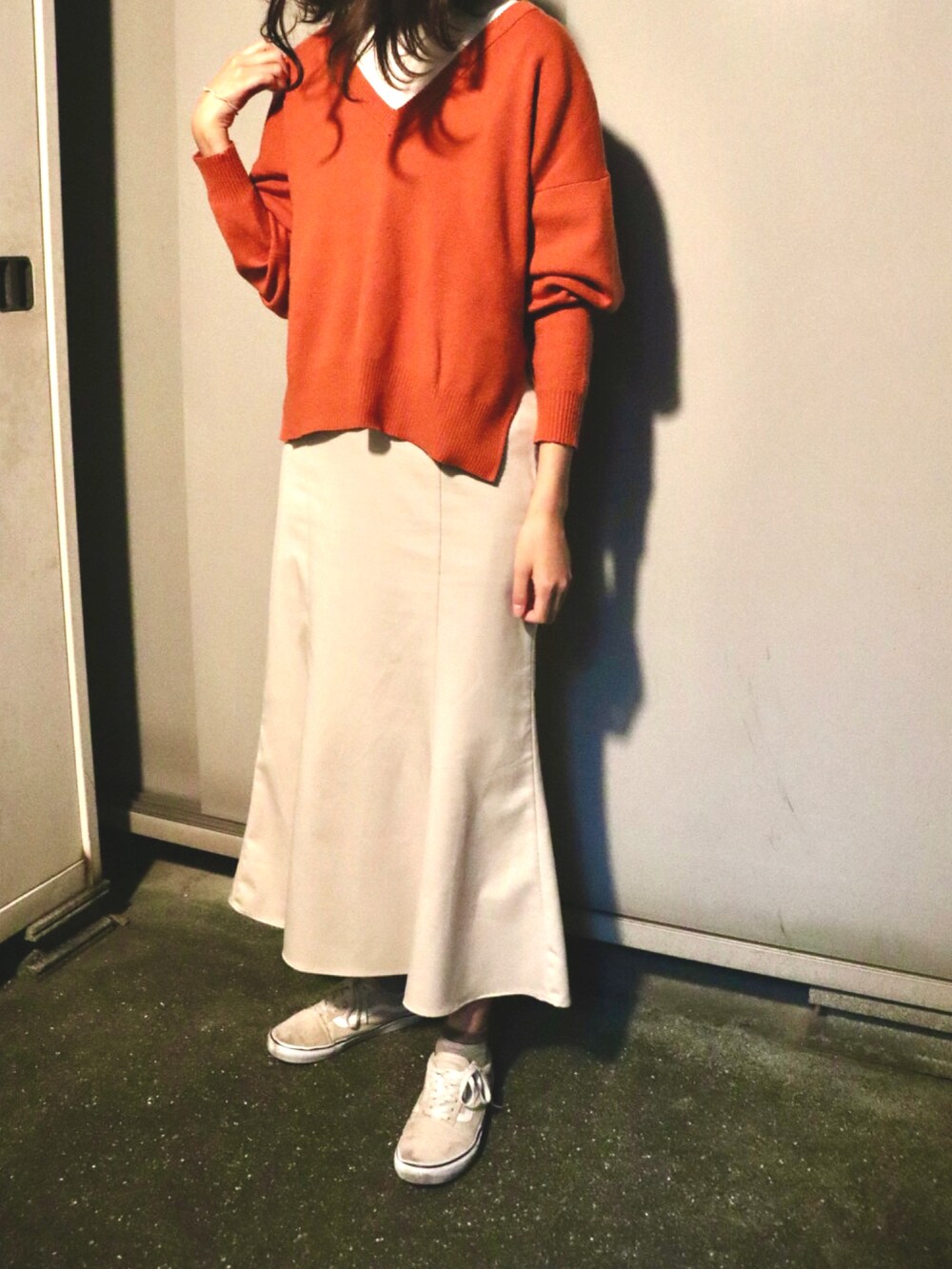 ホワイト系のスカート、オレンジ系のニット/セーター、ベージュ系のスニーカーを着用したレディースの冬コーディネートの2枚目の写真