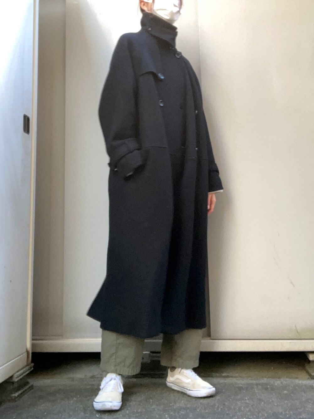 ブラック系のチェスターコート、グリーン系のカーゴパンツ、ベージュ系のスニーカーを着用したレディースの冬コーディネートの2枚目の写真