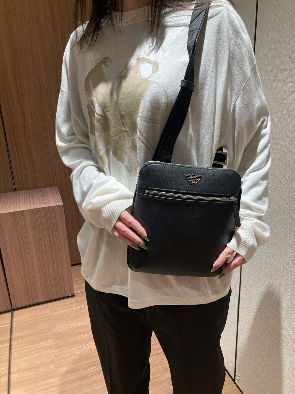 ブラック系のニット/セーター、ブラック系のショルダーバッグ、ブラック系のスニーカーを着用したレディースの春コーディネートの3枚目の写真