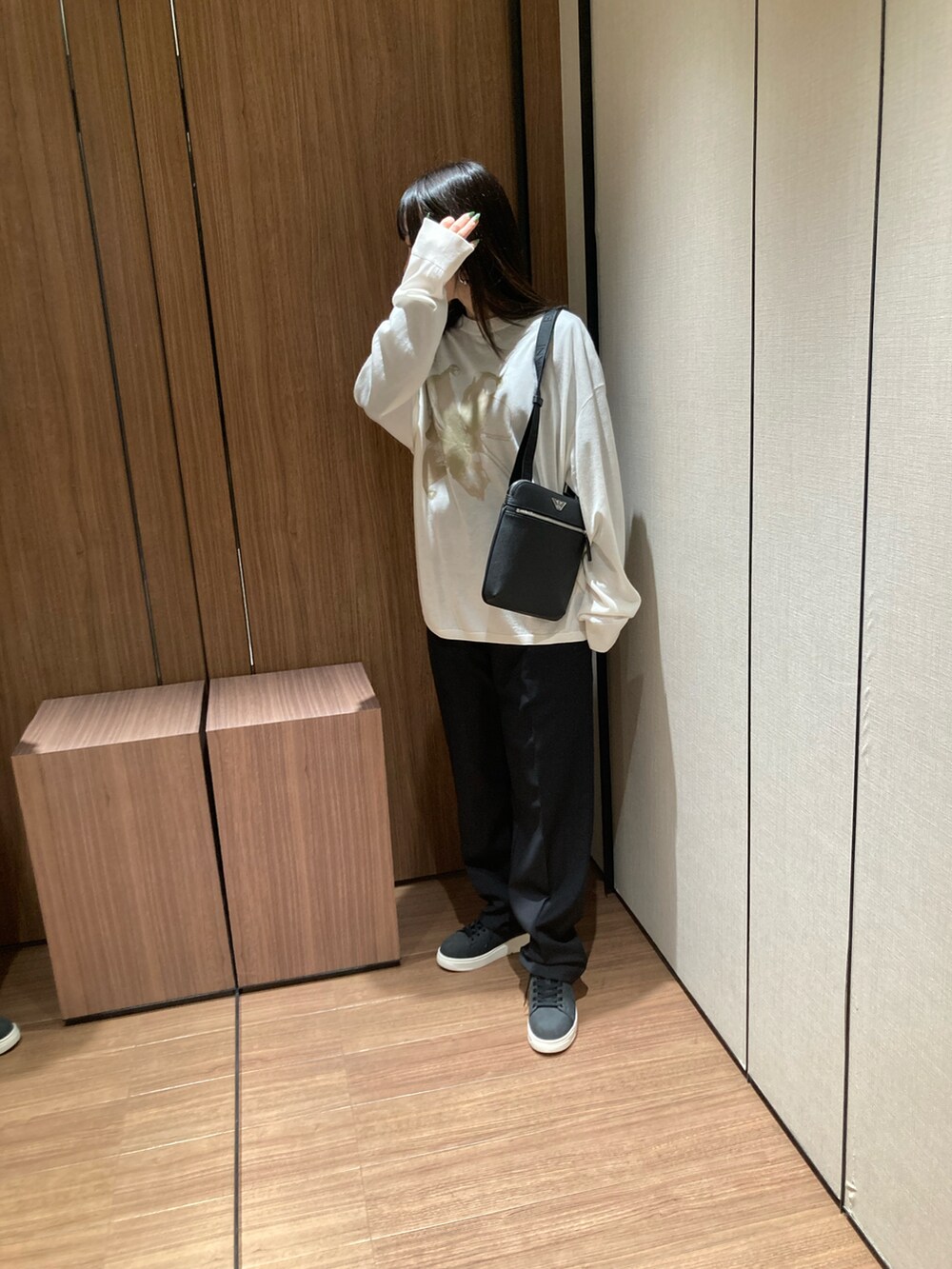 ブラック系のニット/セーター、ブラック系のショルダーバッグ、ブラック系のスニーカーを着用したレディースの春コーディネートの2枚目の写真