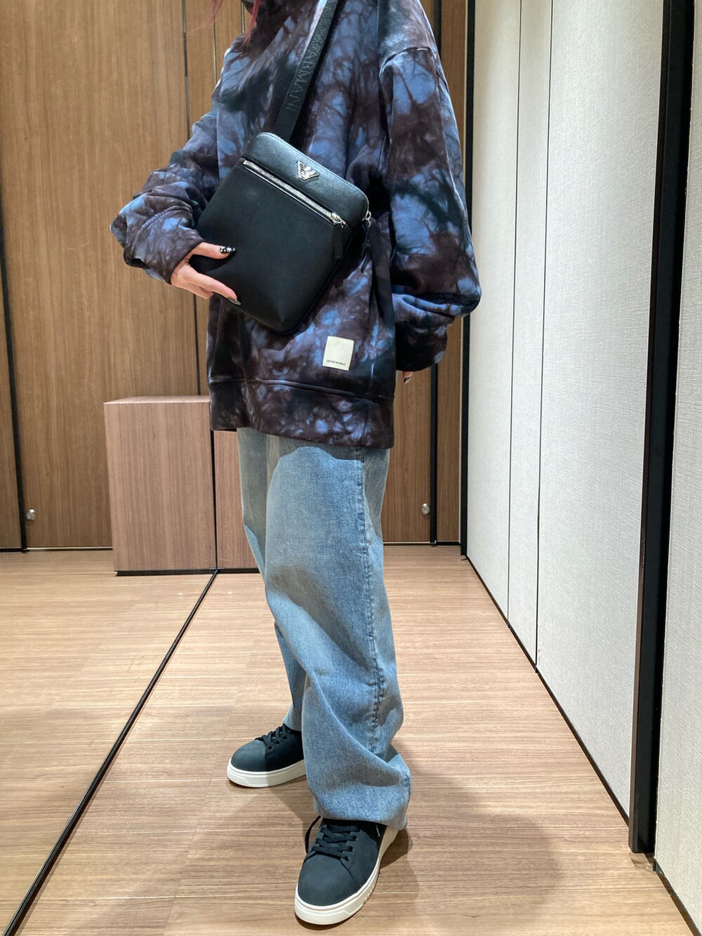 ブルー系のスウェット、ブラック系のショルダーバッグ、ブラック系のスニーカーを着用したレディースの冬コーディネートの2枚目の写真