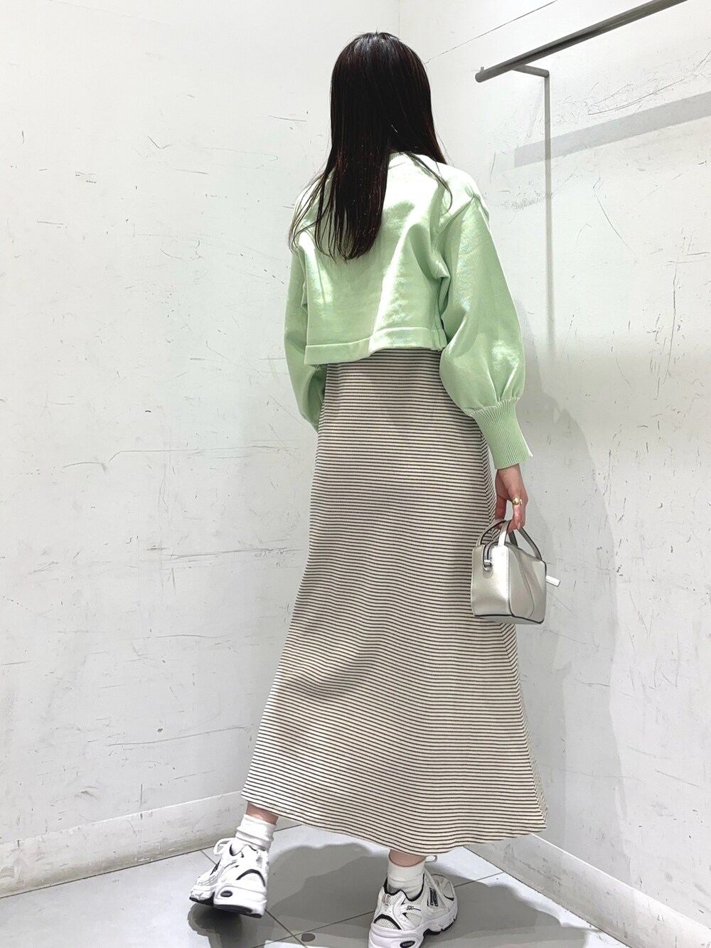 グリーン系のワンピース、ゴールド系のショルダーバッグ、ホワイト系のスニーカーを着用したレディースの冬コーディネートの3枚目の写真