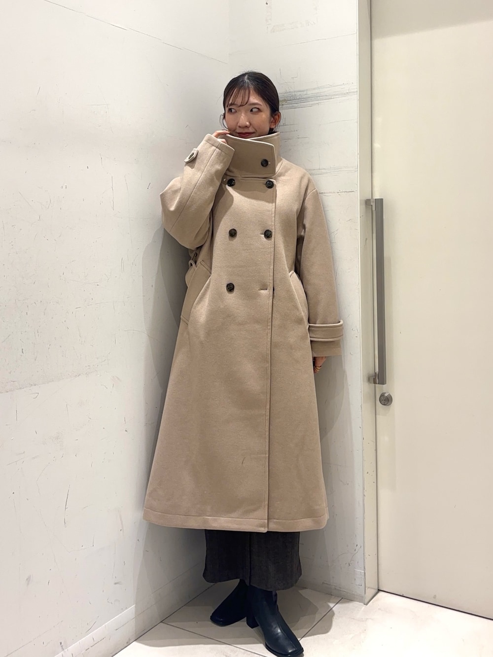 レッド系のカーディガン/ボレロ、ベージュ系のステンカラーコート、ブラウン系のスカートを着用したレディースの秋コーディネートの2枚目の写真
