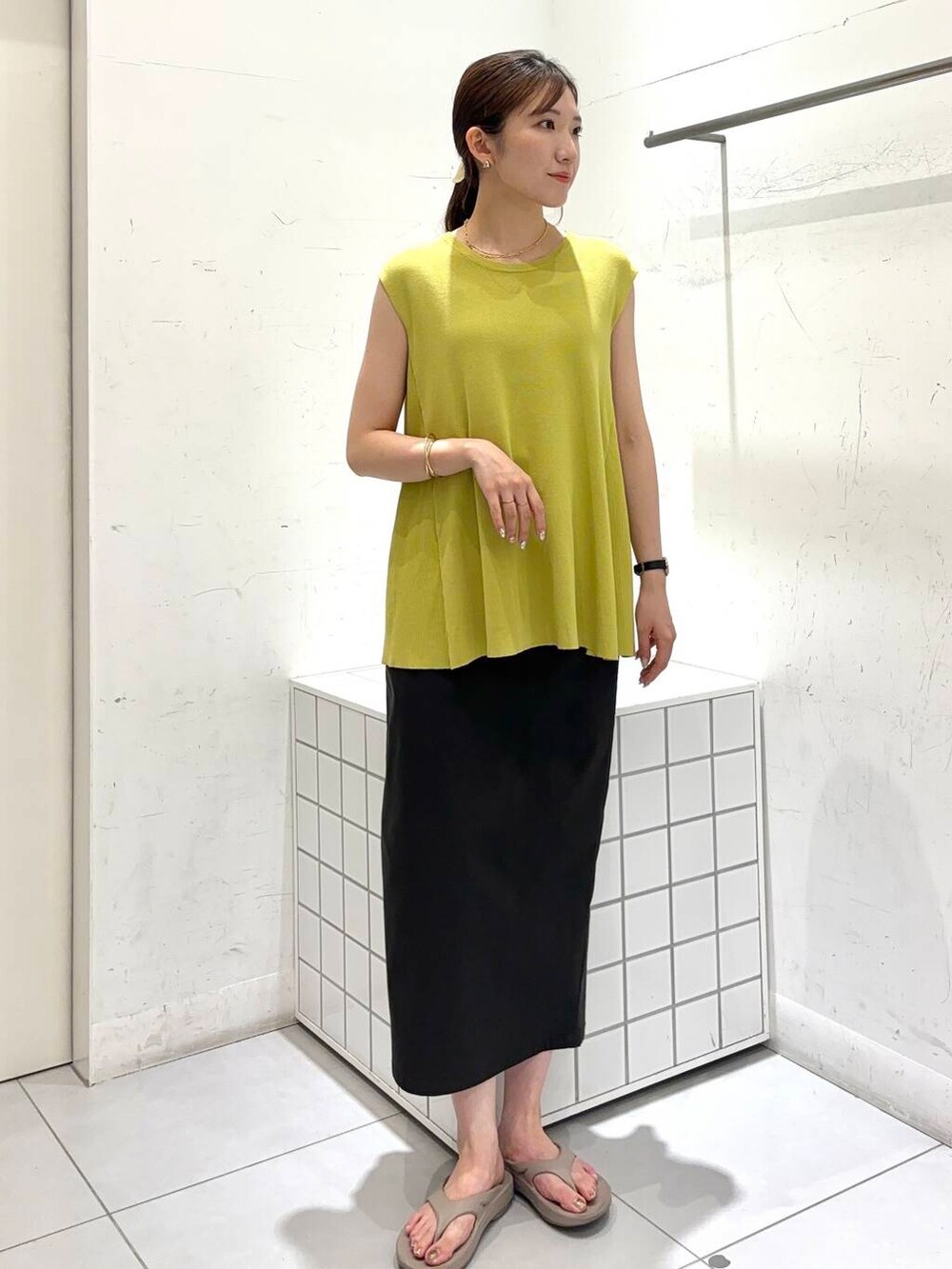 ベージュ系のサンダル、グレー系のスカート、イエロー系のニット/セーターを着用したレディースの夏コーディネートの4枚目の写真