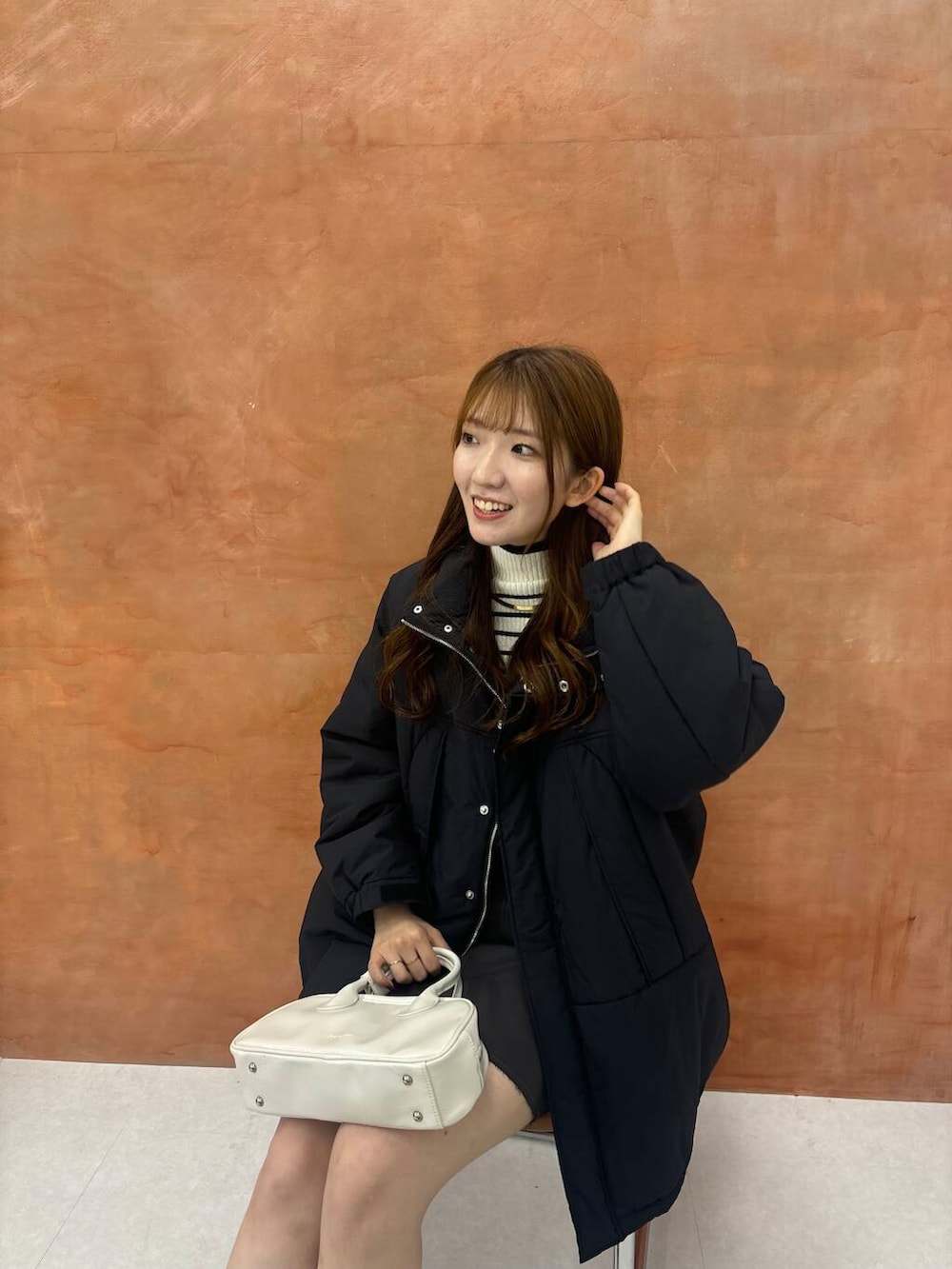 ホワイト系のニット/セーター、グレー系のスカート、ブラック系のダウンジャケット/コートを着用したレディースの秋コーディネートの3枚目の写真