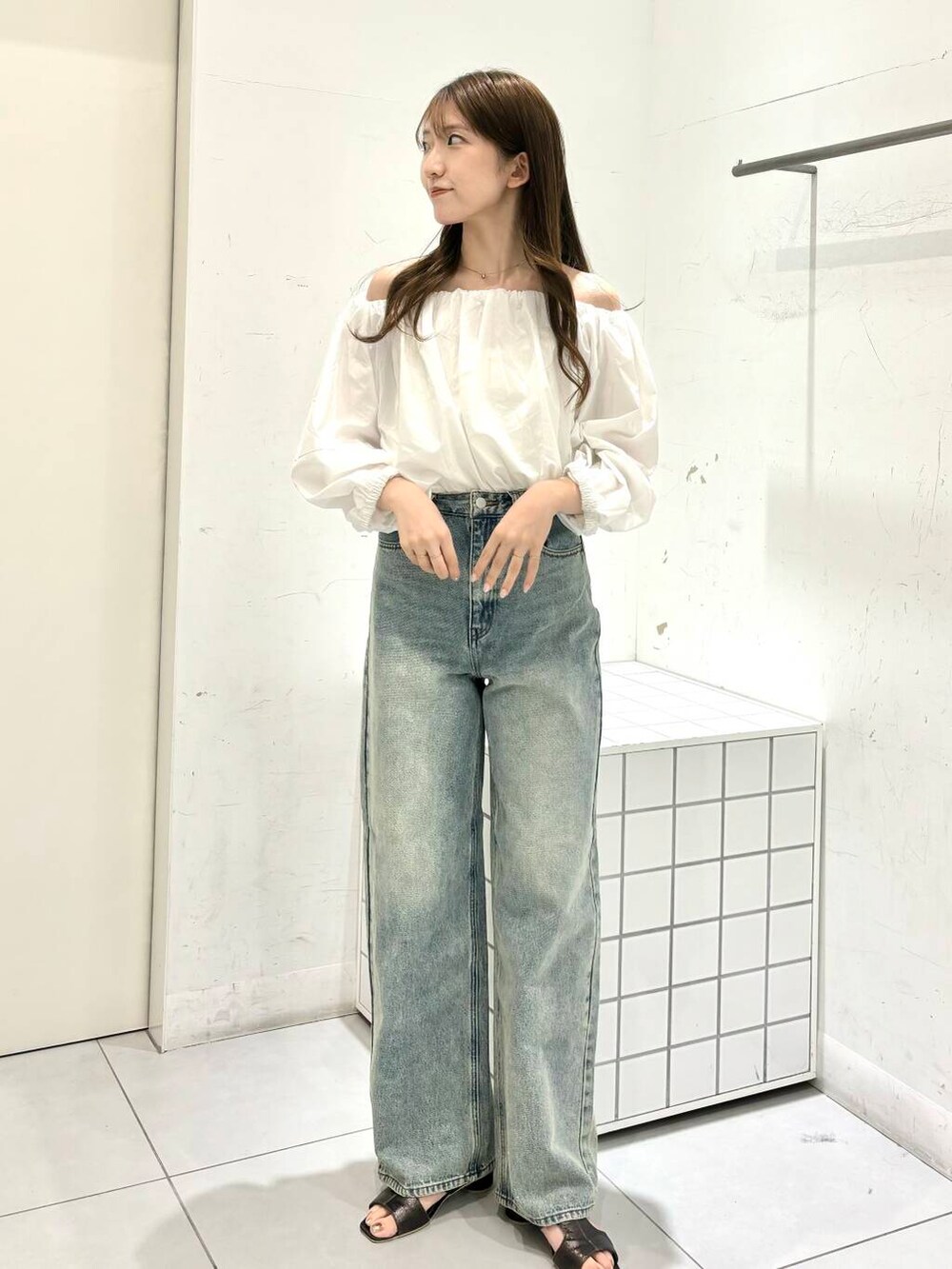 グレー系のサンダル、ホワイト系のシャツ/ブラウス、ブルー系のデニムパンツを着用したレディースの夏コーディネートの2枚目の写真