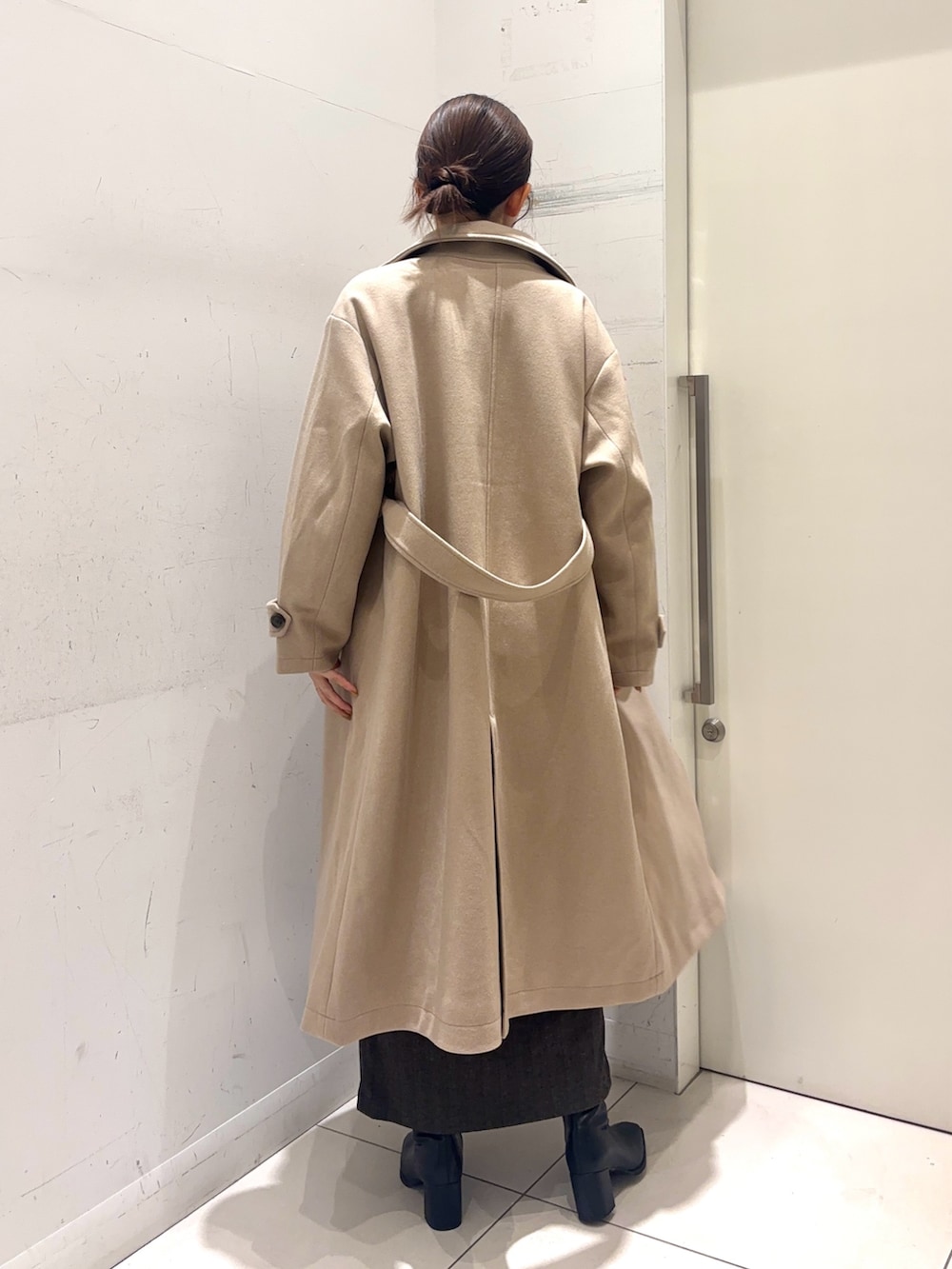 レッド系のカーディガン/ボレロ、ベージュ系のステンカラーコート、ブラウン系のスカートを着用したレディースの秋コーディネートの4枚目の写真