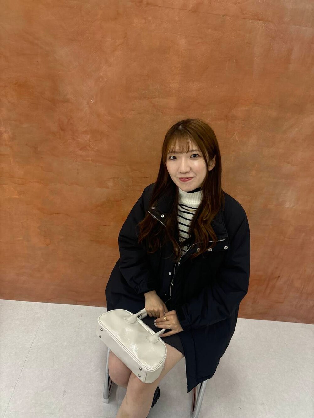 ホワイト系のニット/セーター、グレー系のスカート、ブラック系のダウンジャケット/コートを着用したレディースの秋コーディネートの4枚目の写真