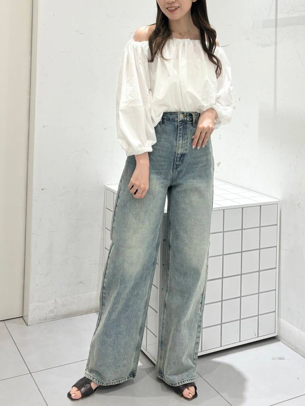 グレー系のサンダル、ホワイト系のシャツ/ブラウス、ブルー系のデニムパンツを着用したレディースの夏コーディネートの3枚目の写真