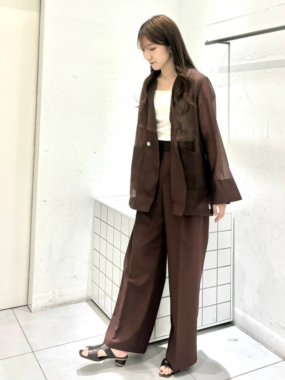 グレー系のサンダル、ホワイト系のキャミソール、ブラウン系のテーラードジャケットを着用したレディースの夏コーディネートの3枚目の写真