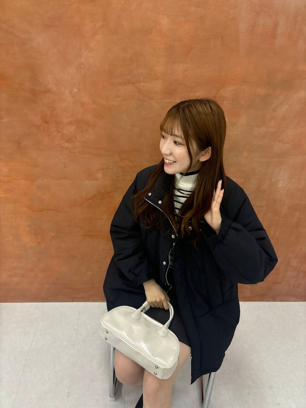 ホワイト系のニット/セーター、グレー系のスカート、ブラック系のダウンジャケット/コートを着用したレディースの秋コーディネートの2枚目の写真