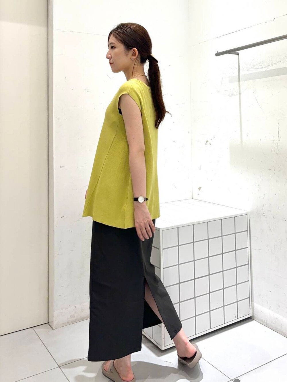 ベージュ系のサンダル、グレー系のスカート、イエロー系のニット/セーターを着用したレディースの夏コーディネートの3枚目の写真