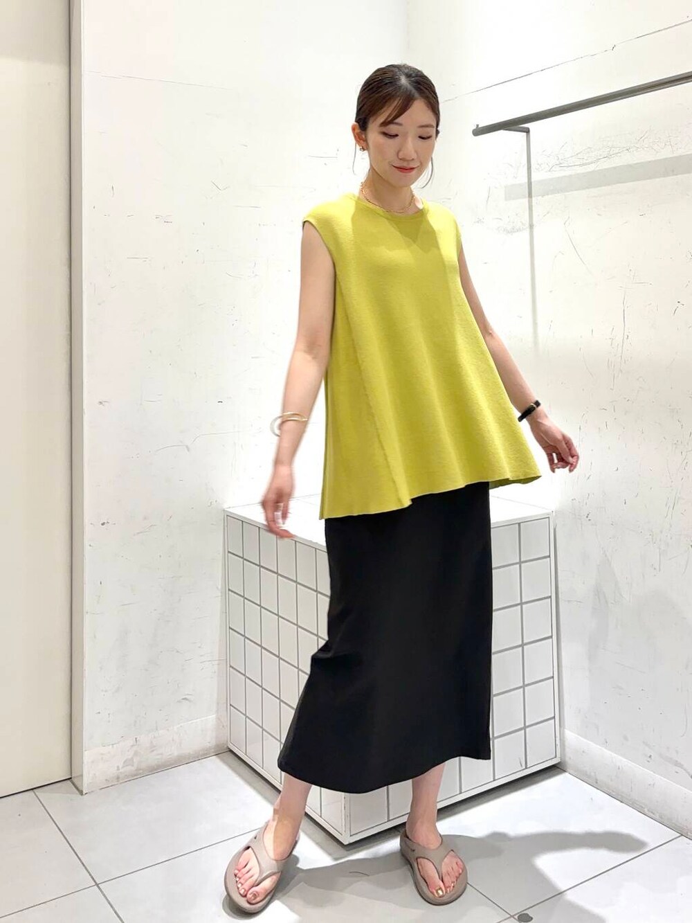 ベージュ系のサンダル、グレー系のスカート、イエロー系のニット/セーターを着用したレディースの夏コーディネートの2枚目の写真