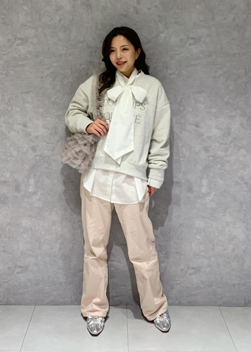 シルバー系のパンプス、ピンク系のデニムパンツ、ベージュ系のショルダーバッグを着用したレディースの冬コーディネートの2枚目の写真