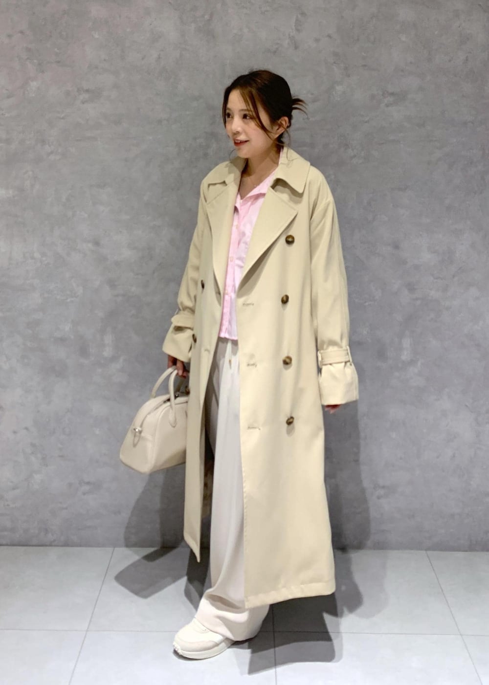 ベージュ系のボストンバッグ、ピンク系のシャツ/ブラウス、ベージュ系のトレンチコートを着用したレディースの春コーディネートの3枚目の写真