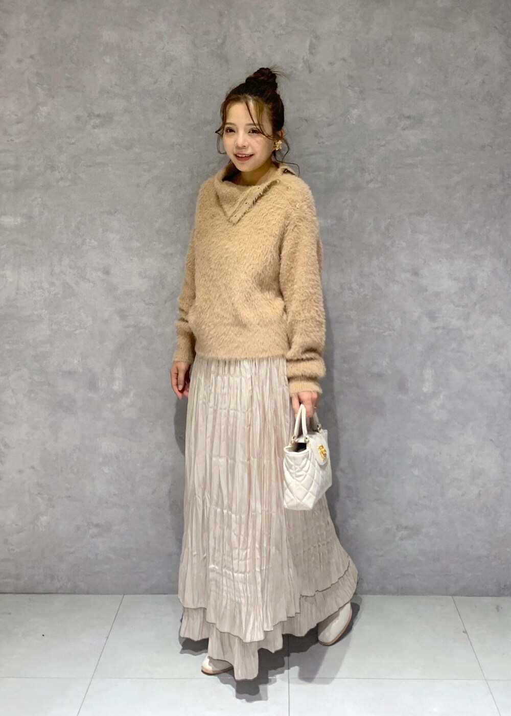 ホワイト系のブーツ、ベージュ系のスカート、ベージュ系のニット/セーターを着用したレディースの冬コーディネートの3枚目の写真
